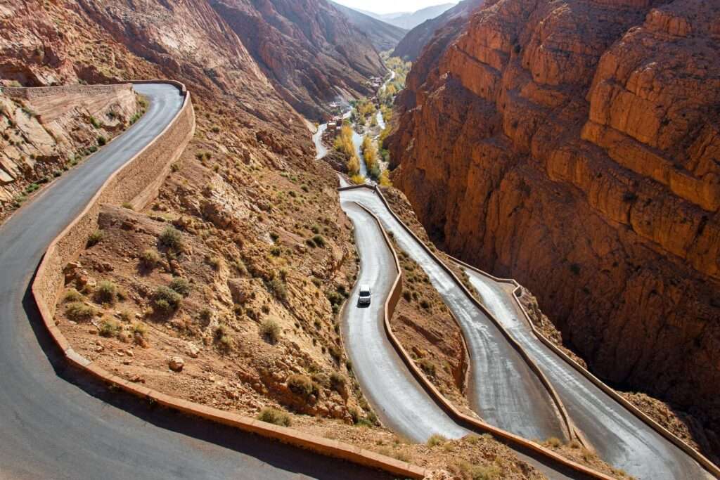 Scenic winding road in Dades Valley during a 4-day Sahara Desert tour from Marrakech, with High Atlas Mountains in the background.